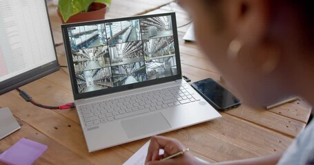 Poster - African american female security officer watching cctv camera views on laptop, slow motion
