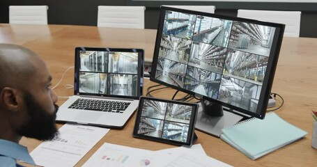 Poster - African american male security officer with business cctv camera views on three screens, slow motion