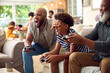 © Monkey Business - Multi-Generation Male Family Sitting On Sofa At Home Playing Video Game With Dad Cheating