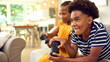 © Monkey Business - Brother And Sister Sitting On Sofa At Home Playing Video Game Together