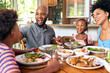 © Monkey Business - Family Sitting Around Table At Home Enjoying Meal Together