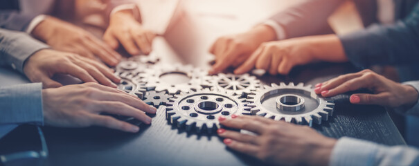 People joining cog wheel on the black desk.