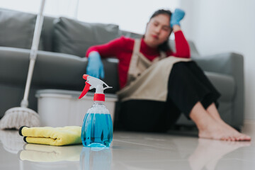 Portrait of beautiful Asian housewife feeling tired after doing housework She sat on the floor in the living room with cleaning equipment.