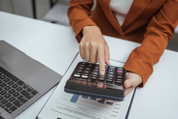 Close up hands of woman in brown formal suit checking bills, taxes, bank account balance, using calculator, Personal Checking, Empower Checking, Personal Savings, Certificates, IRAs, Money Market