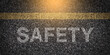 © Gabriele - Textured asphalt with 'Safety' text on the road under a yellow line, rough surface of tarmac with the word 'Safety' written, caution message on pavement, road safety concept