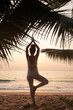 Woman practicing yoga by the ocean at dawn
