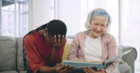 Wall Mural - Photo album, assisted living and a happy senior with her black woman caregiver on a sofa in the living room. Smile, funny and elderly resident laughing at a memory with a nurse in a retirement home