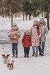 Happy young caucasian family plays with two dogs in winter in a pine forest. The concept of Christmas and New Year