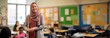 © ViktoGraphics - A school teacher in elementary class, teaching children, copy space. Created with Generative Ai technology.