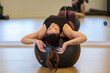 © Mat Hayward - Physically fit woman stretching her back on an exercise ball in gym during workout.