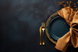 Golden cutlery on black background. Black empty ceramic plate with golden fork and knife. Fashionable and luxury eating. Flat-lay, top view. Copy space for your text.