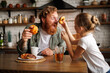 © Dmytro Hai - Father having fun with daughter and pastry during breakfast in kitchen