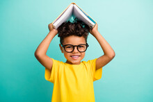 Portrait Of Adorable Small Boy With Brown Hair Wear Stylish T-shirt In Glasses Hold Book Over Head Isolated On Teal Color Background