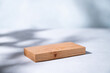 Wooden board empty for product demonstration or mock-up with shadows on a blue background. Rectangular stand for cosmetics or advertising items.