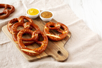 Wall Mural - Homemade Soft Bavarian Pretzels with Mustard on a wooden board, side view. Space for text.