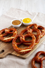 Wall Mural - Homemade Soft Bavarian Pretzels with Mustard on a wooden board, side view. Copy space.