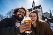 © Romana - Two young cheerful people drinking beer on a winter vacation, a castle in the background