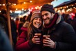 Two young cheerful people drinking mulled wine at the christmas market on a winter vacation