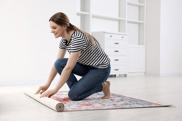 Sticker - Smiling woman unrolling carpet with beautiful pattern on floor in room