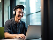 © Kedek Creative - Smiling Asian male office worker wearing headphones in front of laptop working and making video call