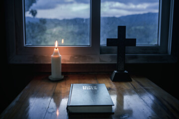 Poster - Light candle with holy bible on wooden table at window background, Bible study concept.