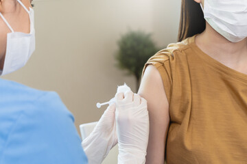 People getting a vaccination to prevent pandemic concept. Woman in medical face mask  receiving a dose of immunization coronavirus vaccine from a nurse at the medical center hospital