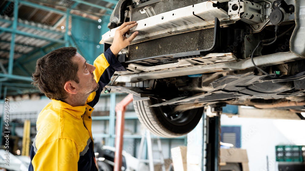 Vehicle mechanic conduct car inspection from beneath lifted vehicle ...