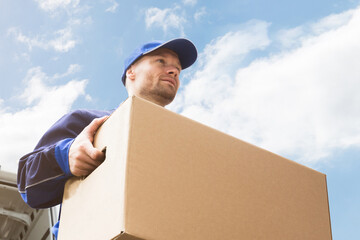 Close-up Of Two Delivery Men Carrying Cardboard Box