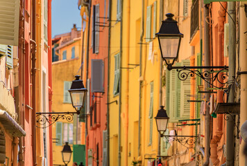 Poster - Picturesque old street light, colorful traditional houses with shutters in the background in the old town of Menton, French Riviera, South of France