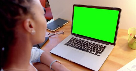 Wall Mural - African american casual businesswoman at desk watching laptop with green screen, slow motion