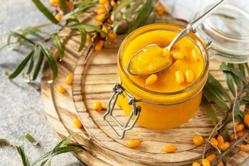 Wall Mural - Homemade jelly, jam from a sea-buckthorn in glass jar of an organic sea-buckthorn on a stone background.