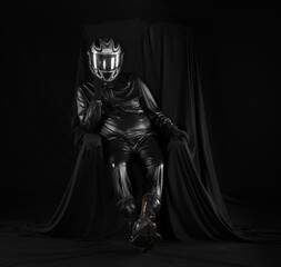 Wall Mural - portrait of a biker in a helmet on a chair on a black background