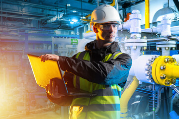 Poster - Engineer with laptop. Man with computer. Engineer in basement of industrial building. Industrialist man in protective helmet. Factory employee. Gas pipes behind guy. Chemical factory engineer
