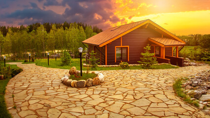 Wall Mural - Country house. Sunset over village mansion. Single storey wooden cottage. Country villa on summer evening. Stone path leads to house. Landscape with wooden house. Eco property at sunset