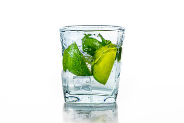 A glass of water with lime and ice on a white background.