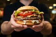 A tantalizing close up of a beefy burger gripped by a mans hungry hands