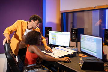 Cheerful diverse podcast networking ethnic colleagues gathered near computers table in studio