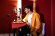 © ADDICTIVE STOCK - Cheerful young ethnic man sitting and recording podcast with microphone in studio