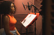 © ADDICTIVE STOCK - Focused black female standing and recording song near microphone equipment in studio