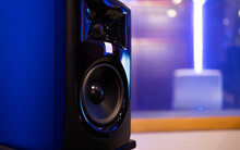 Loud Speakers Enclosed In Black Studio Monitor Placed On Table In Blurred Room