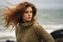 Young Woman In Sweater Stands On Windy Winter Seashore