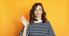 Be Quiet. Attractive Playful Woman Uses Sign Language Zips Mouth With Hands Asks To Keep Secret Has Mysterious Happy Look Poses Against Yellow Background.