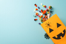 Experience Magic Of Kids' Halloween Treat Tradition. Top-view Shot Featuring Pumpkin Basket, Sweets And Halloween Decorations On An Blue Isolated Surface, Suitable For Text Or Promotional Material