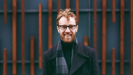 A young red-haired guy, a businessman in glasses, looks at the camera against the background of an urban style. Close up portrait