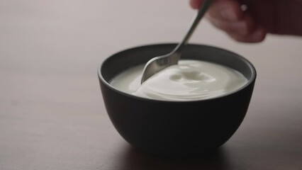 Wall Mural - Slow motion scoop organic yogurt in black bowl on wood table