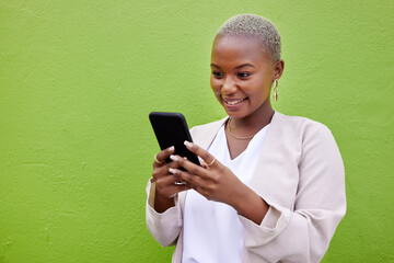 Poster - Black woman, typing and phone for communication by a wall or green background with internet. African person with a smartphone reading social media message, networking and mobile app chat space