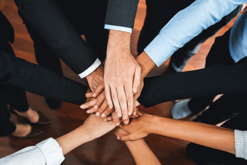 Multiracial business people make synergy hand stack together in meeting room as cooperation or team building for corporate employee in workplace. Meticulous