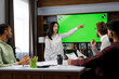 © YURII MASLAK - Marketing strategy analysis, stock market trading or corporate teamwork. A team of startups at a table with a large green screen TV. Mixed race business team.