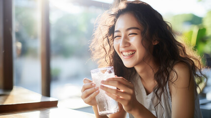 Young woman holds a glass of water in her hand and smiles