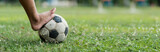 Fototapeta Sport - Close up of a old soccer, boy not wearing shoes ready to kicks the ball at the old football field.